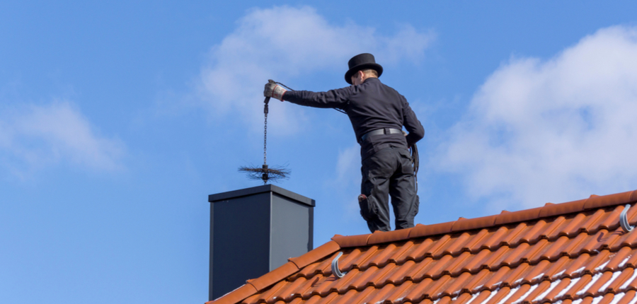 cleaning a chimney standing on the house roof
