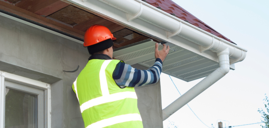 construction worker mounts a soffit on the roof