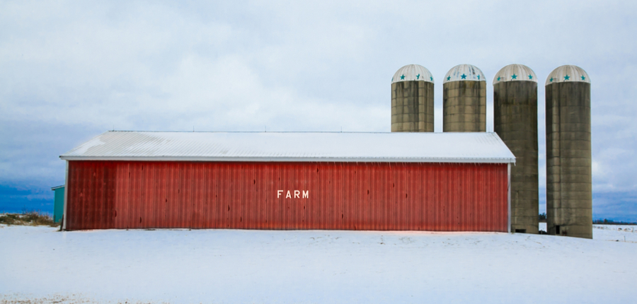 red pole barn with four silos