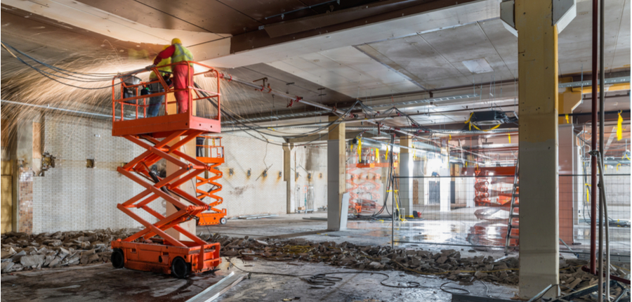 workers at construction site standing on rented scissor lift